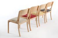 Als Stuhlreihen laden die Dheli Holzstühle zum Sitzen ein