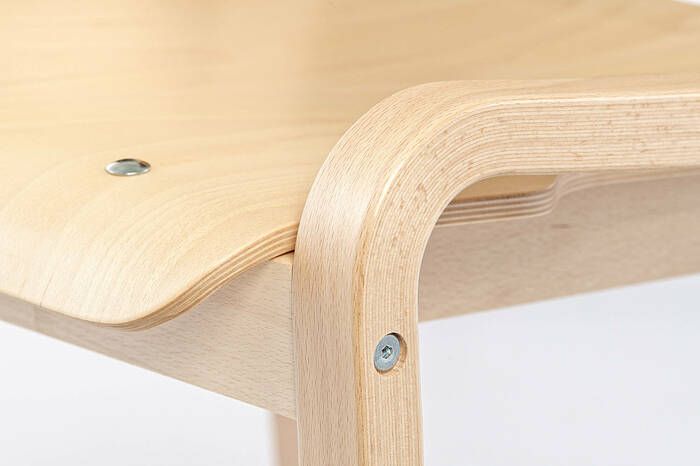 Die Holzsitzfläche ist dem Stuhlgestell angepasst